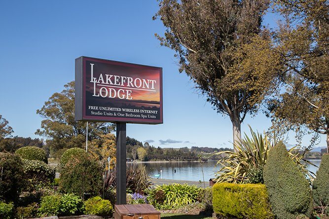 Close up of Lakefront Lodge sign with Lake Te Anau in the background